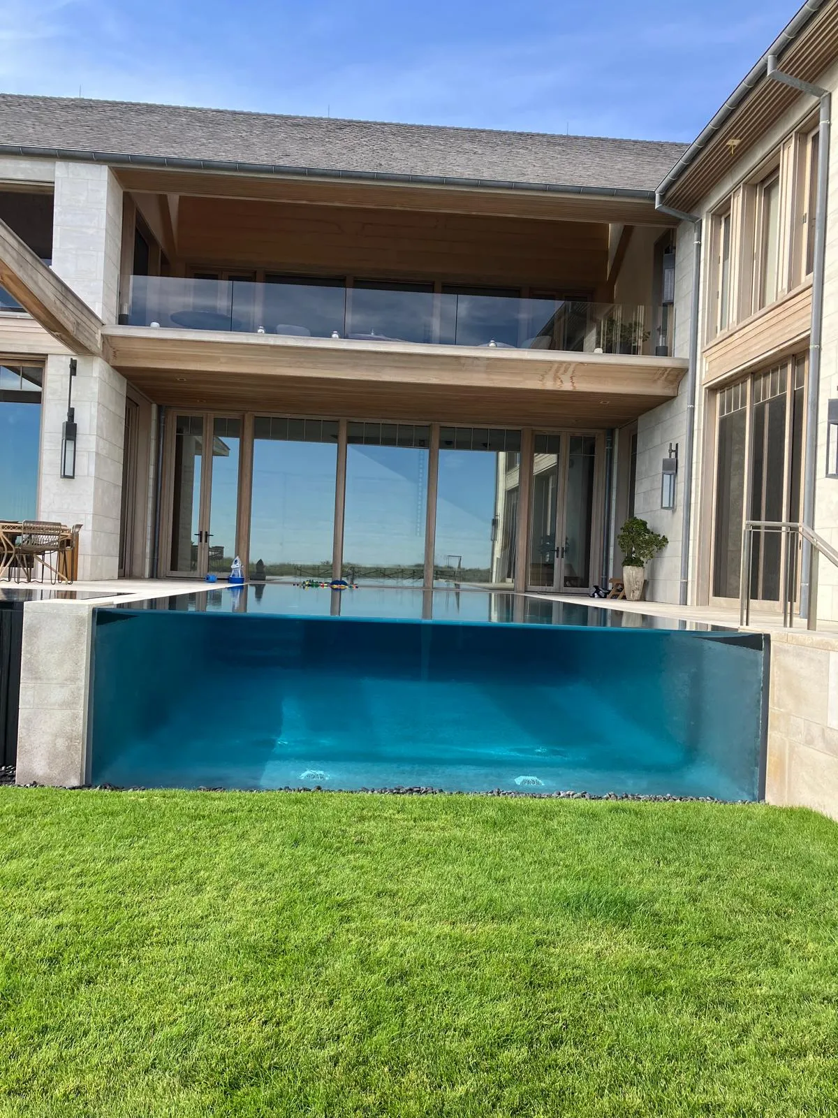 A glass-walled swimming pool beside a lawn.